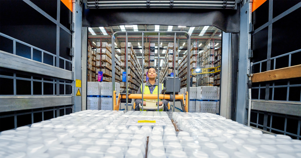 Healthcare warehouse worker operating forklift moving medical supplies pallets for freight logistics