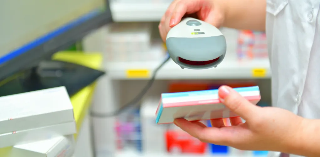 Hands using a scanner on a medical supply box in a pharmacy